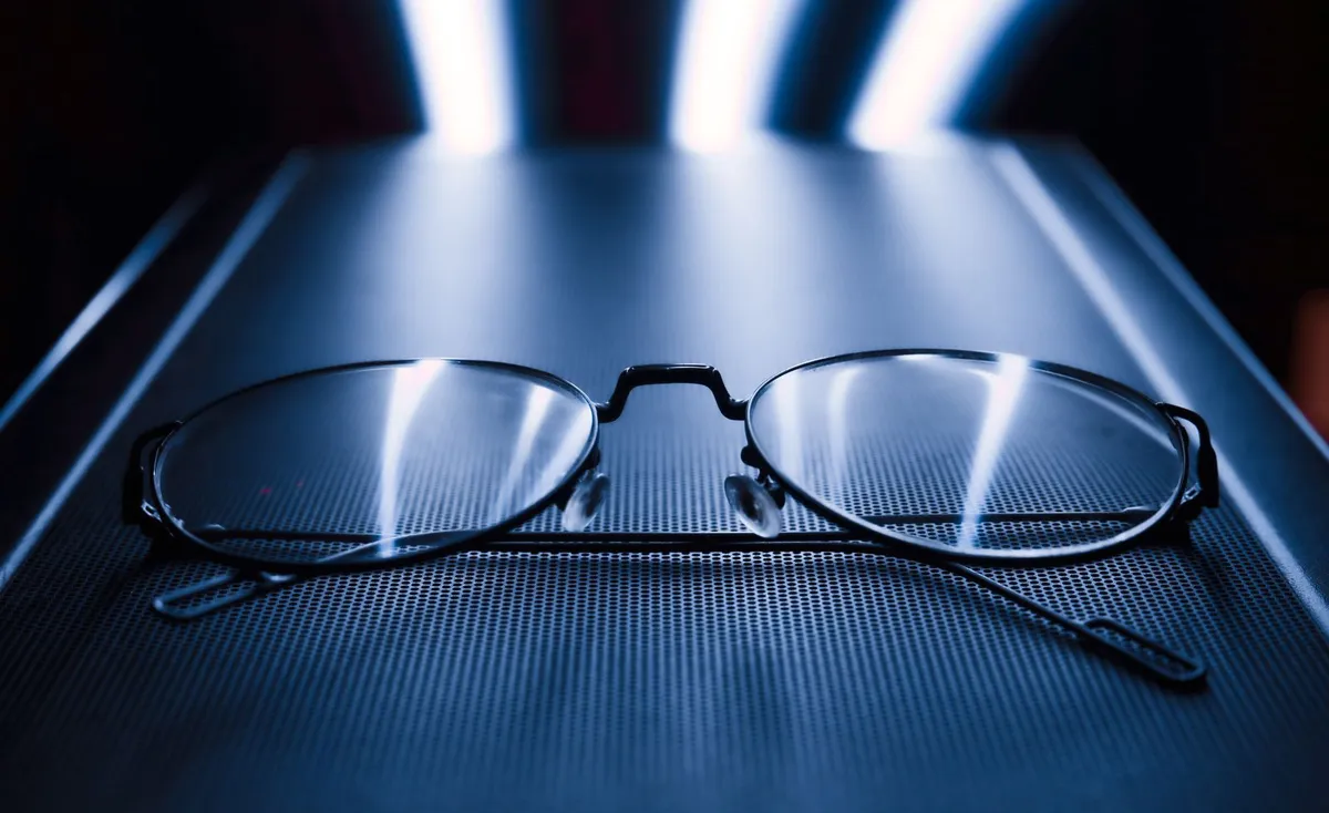Primer plano de unas gafas elegantes sobre un fondo azul oscuro con reflejos