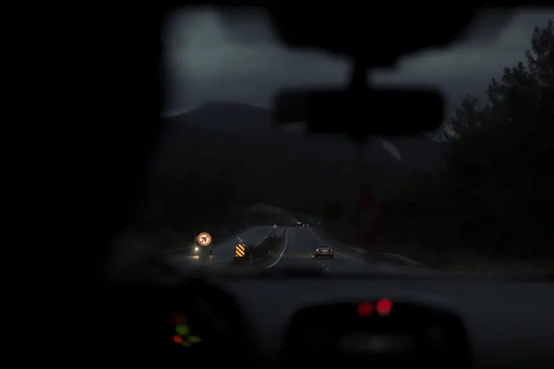 Vista de una autopista de noche desde el interior de un coche con los faros encendidos