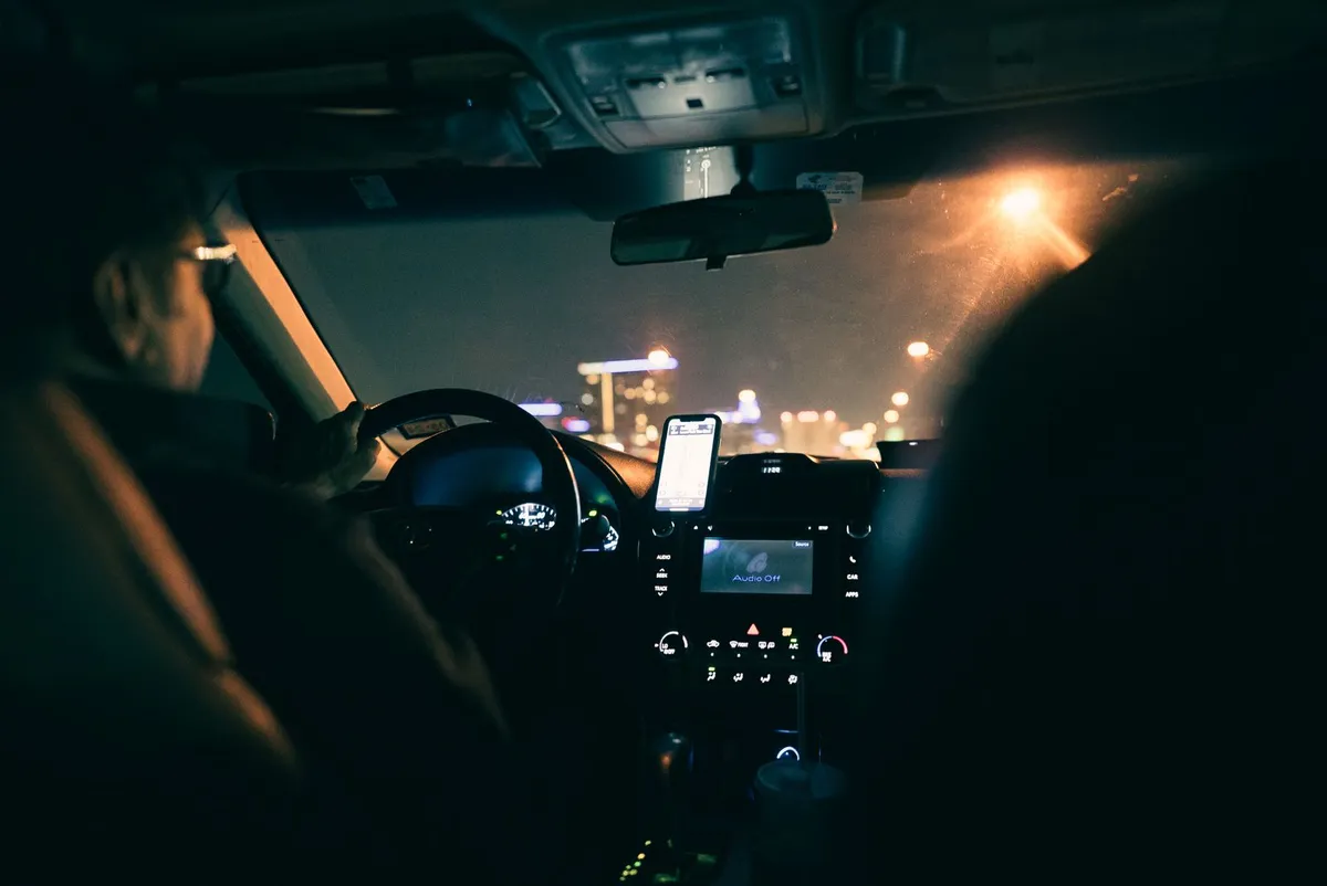 Un hombre con gafas conduciendo un coche de noche por la ciudad