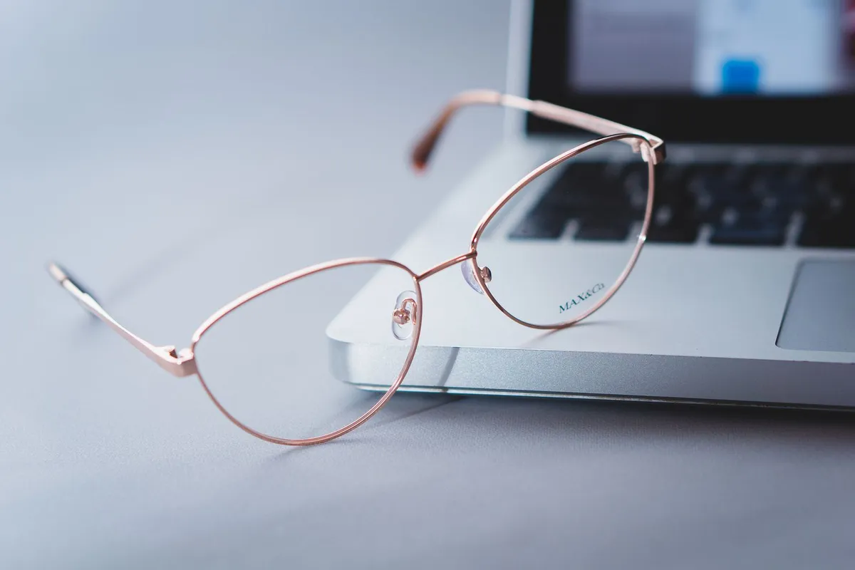 Unas gafas colocadas junto a un ordenador portátil sobre una mesa