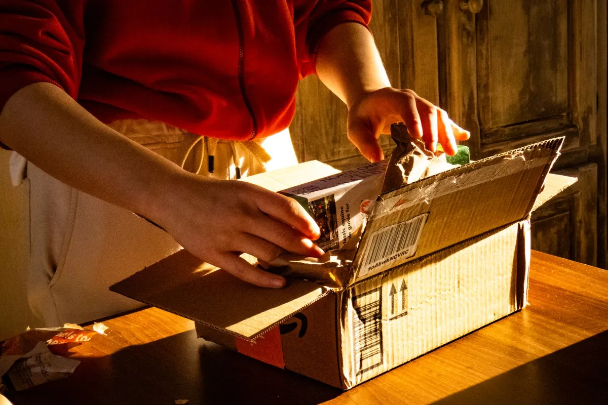 Unas manos abriendo un pequeño paquete bajo una luz cálida