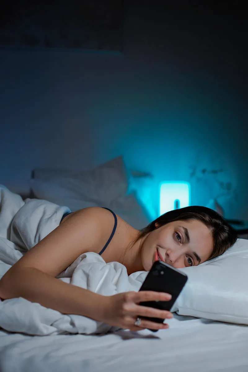 Persona usando el móvil en la cama a oscuras antes de dormir