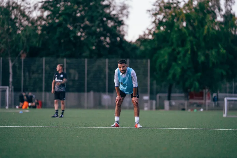 Un jugador de fútbol con equipación apoyado en el suelo durante un entrenamiento
