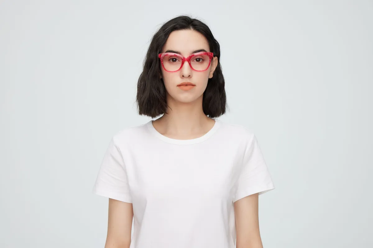 Una mujer joven con camisa blanca luciendo unas gafas de montura roja
