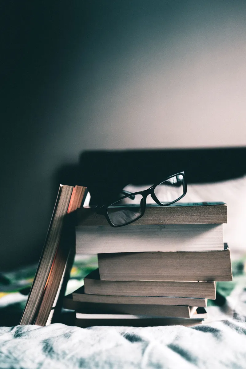 Unas gafas de montura negra descansando sobre una pila de libros