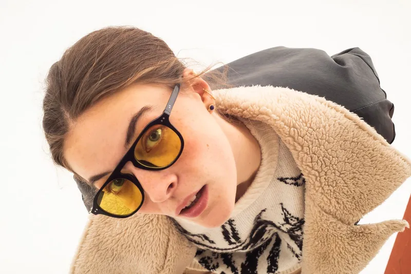 Una mujer con gafas de sol amarillas y expresión curiosa