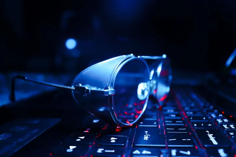 Gafas apoyadas sobre el teclado iluminado de un portátil por la noche